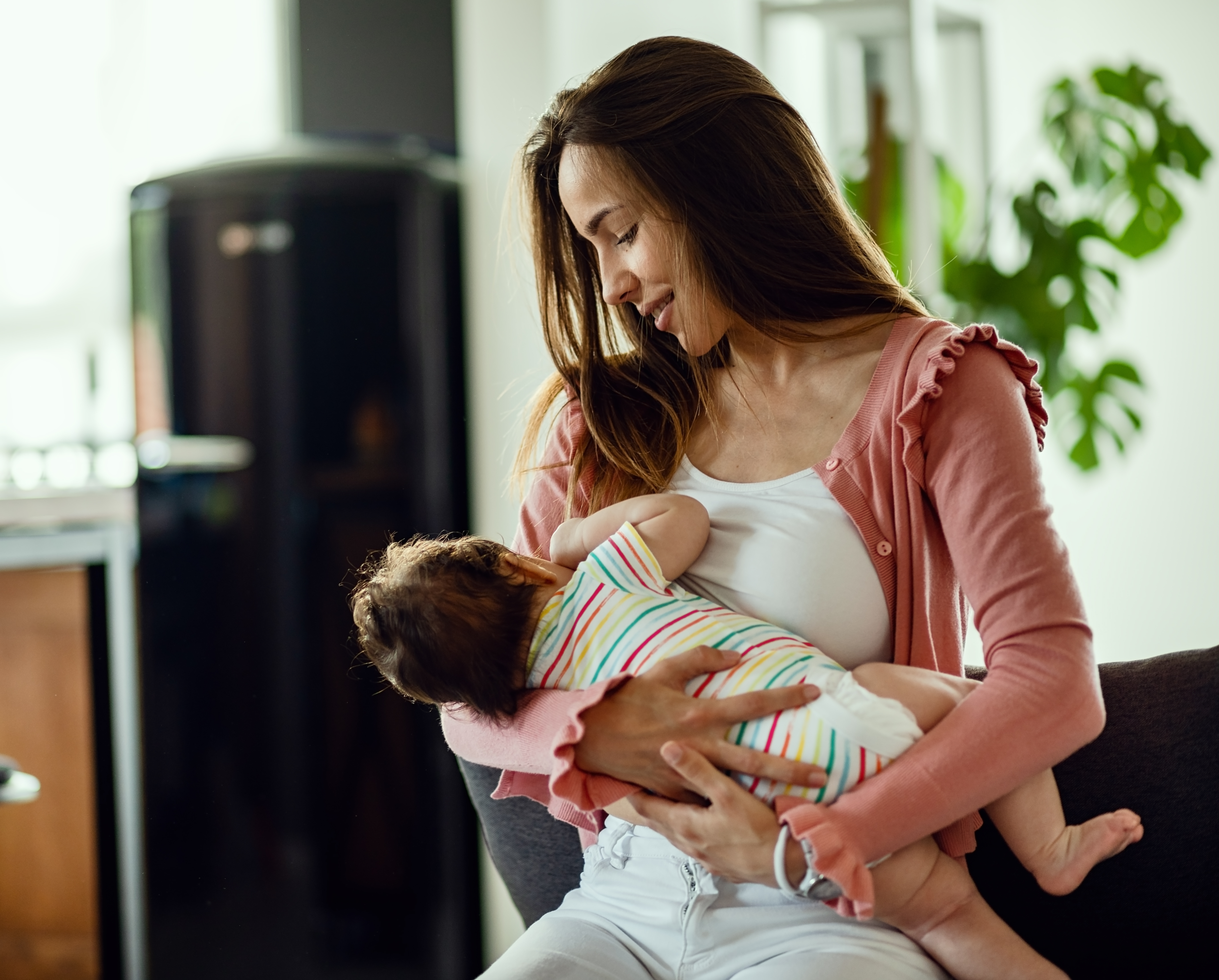 2smiling mother breastfeeding her baby daughter while being at home